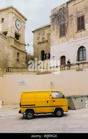 Photo verticale d'une fourgonnette jaune garée près d'une église Banque D'Images