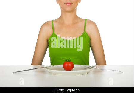 Femme dans la cuisine avec une tomate sur la plaque en face d'elle Banque D'Images