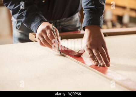 Carpenter measuring et le traçage des lignes avec une règle sur une surface en bois. Banque D'Images