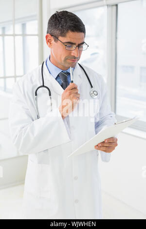 Médecin homme concentré la lecture de rapports à l'hôpital Banque D'Images