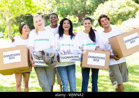 Portrait de groupe de joyeux bénévoles transportant des boîtes de dons dans la région de park Banque D'Images