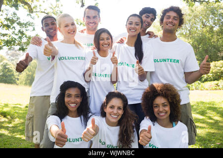 Portrait de groupe de bénévoles convaincus gesturing Thumbs up in park Banque D'Images