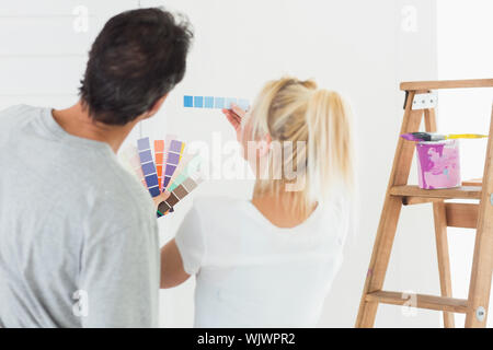 Vue arrière d'un couple de choisir la couleur pour peindre une pièce contre fond blanc Banque D'Images