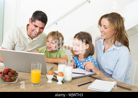 Family using laptop pendant le petit-déjeuner à la maison Banque D'Images