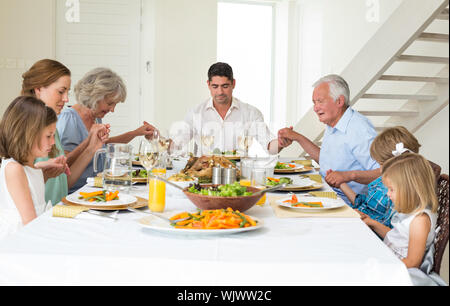 Famille multigénérationnelle priant ensemble avant le repas à table à manger Banque D'Images