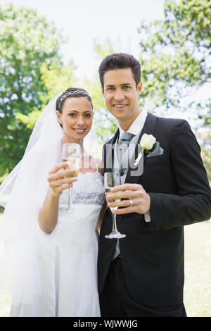 Portrait of Bride and Groom toasting with champagne in park Banque D'Images