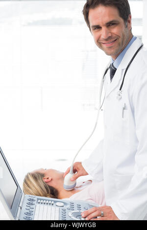 Portrait of male doctor using sonogramme sur le cou du patient de sexe féminin Banque D'Images