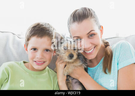 Smiling woman holding her yorkshire terrier chiot avec son fils à la maison dans le salon Banque D'Images