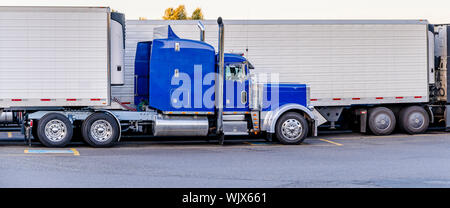 Big Rig classic American Idol de qualité industrielle bleu semi truck avec tuyaux de transport de fret en chrome réfrigérateur semi-remorque debout sur le chariot Banque D'Images