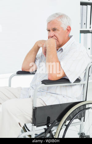 Vue latérale d'un sad senior man sitting in wheelchair at the medical office Banque D'Images