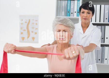 Physiothérapeute senior féminine massant womans de retour dans le bureau médical Banque D'Images