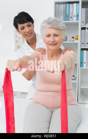 Physiothérapeute senior féminine massant womans de retour dans le bureau médical Banque D'Images