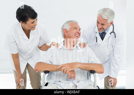 Happy senior patient avec des médecins assis en fauteuil roulant à l'hôpital Banque D'Images