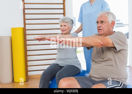 Female therapist aider senior couple avec des exercices dans le bureau médical Banque D'Images