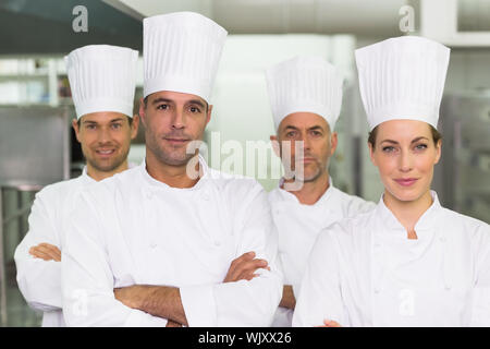 Équipe de chefs heureux regardant la caméra dans une cuisine commerciale Banque D'Images