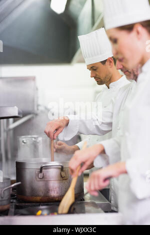 Équipe de cuisiniers de la cuisson à la poêle dans une cuisine commerciale Banque D'Images