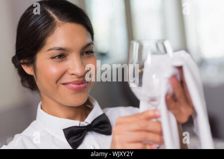 Jolie serveuse polissage d'un verre de vin dans un restaurant chic Banque D'Images