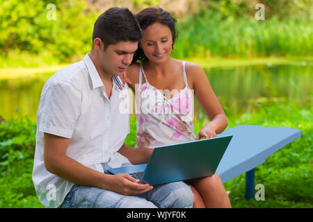 Jeune couple Je suis intéressé dans l'ordinateur portable sur la nature Banque D'Images