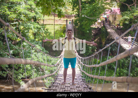 Jeune homme sur le pont suspendu sur la rivière Loboc, Philippines Banque D'Images