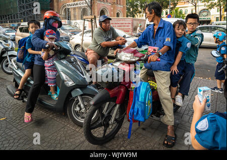 Les parents sur leurs scooters chercher leurs enfants à l'école, Ho Chi Minh City, Vietnam Banque D'Images