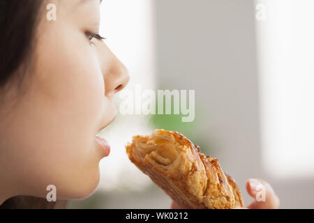 Young Asian woman eating a pastry Banque D'Images