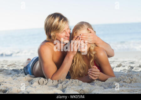 Les yeux de l'homme couvrant des amies sur la plage Banque D'Images