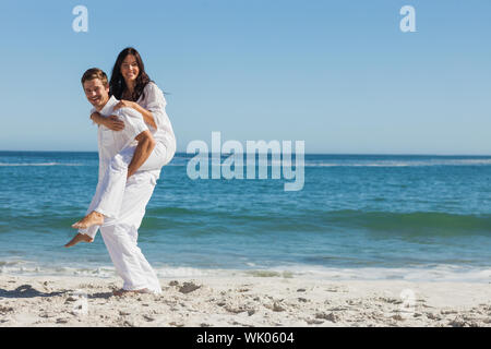 Smiling woman sitting on mans back and looking at camera Banque D'Images