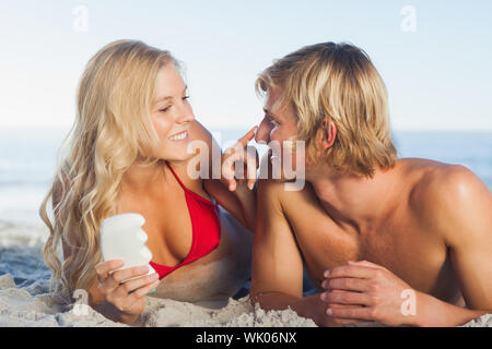 Femme de mettre la crème solaire sur le nez de son partenaire Banque D'Images