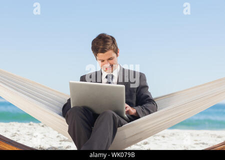 Businessman typing sur son ordinateur portable dans un hamac Banque D'Images