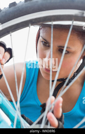 Athletic woman adjusting ses rayons sur la roue de vélo Banque D'Images