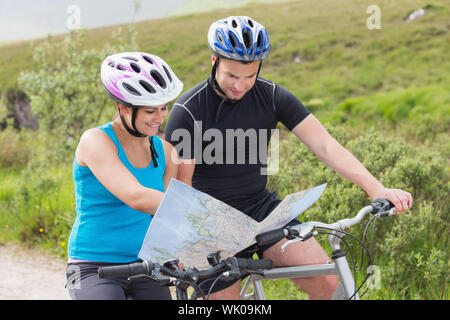 Couple on mountain bikes reading map Banque D'Images