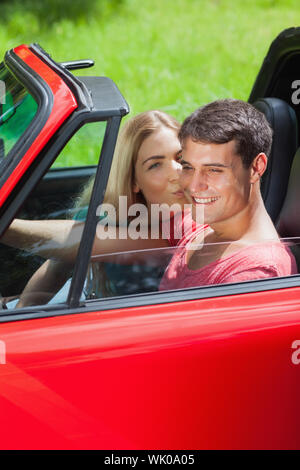 Happy blonde kissing her boyfriend in red cabriolet Banque D'Images