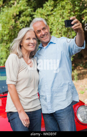 Smiling mature couple prendre des photos d'eux-mêmes Banque D'Images