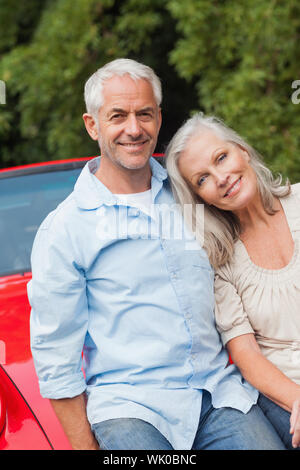 Young couple sitting on their red cabriolet Banque D'Images