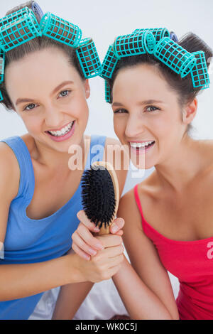 Happy in hair rollers holding hairbrush Banque D'Images