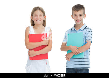 Cheerful brother and sister holding their exercise books Banque D'Images