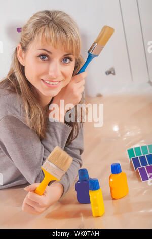 Belle femme peintre se trouve sur un parquet en bois et de tenir deux martre et looking at camera Banque D'Images