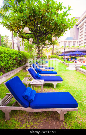 Chaises longues bleu près de la piscine dans complexe de luxe Banque D'Images