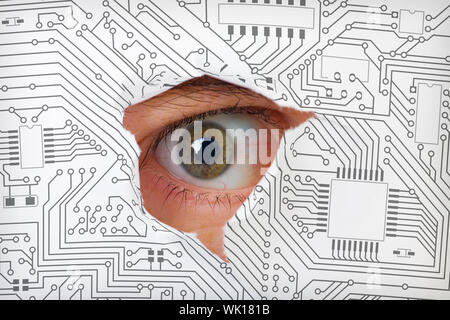 Oeil humain à travers un trou dans le circuit électronique Banque D'Images