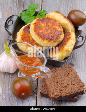 L'Arrangement de La viande de poulet délicieux côtelettes dans une casserole noire avec du pain brun, la sauce et les légumes sur fond de bois. Vue d'en haut Banque D'Images