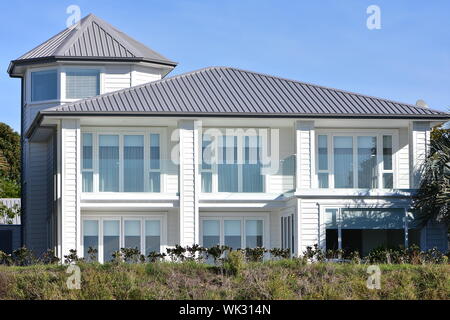 Grande maison en bois blanc de deux étages, avec des murs en verre pour la plupart sur façade et tour à gauche. Banque D'Images