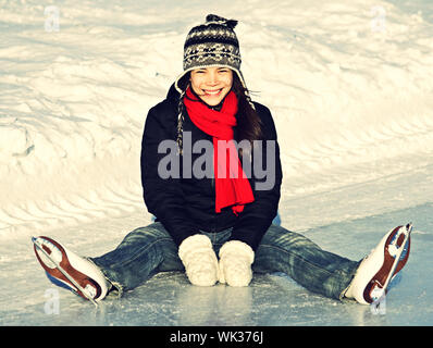 Patin à glace femme assise sur la glace en souriant. Banque D'Images