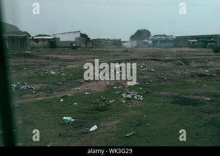 Jamestown, Accra, Ghana - Dec 26, 2017 : Colporteur man selling shoes est seul dans une plage pleine d'ordures dans un village de pêcheurs. En bois traditionnel Banque D'Images