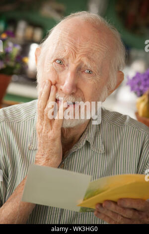 Senior man at home reading carte de condoléances Banque D'Images