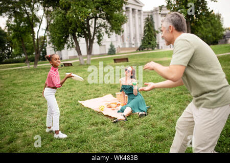 Jeter tout en jouant la fille de frisbee et s'amusant avec papa Banque D'Images