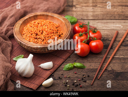 Plaque en bois bol de riz à la tomate et basilic et l'ail et de baguettes en bambou brun sur place mat sur fond de bois sombre avec un chiffon. Vue d'en haut. Banque D'Images