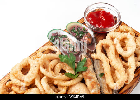 Les moules et d'oignon frit, de calmars et de poissons frits à la pâte sur une planche à découper, sauce, isolé sur un fond blanc. Banque D'Images