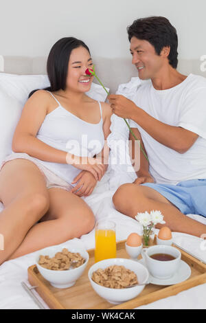 Couple heureux de prendre le petit déjeuner au lit à la maison dans la chambre Banque D'Images