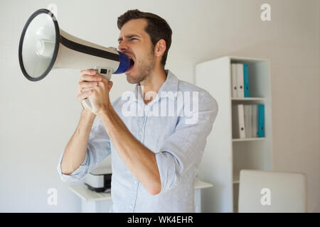 Businessman shouting par mégaphone dans son bureau Banque D'Images