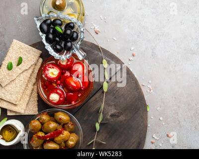 Ingrédients de cuisine italienne avec des craquelins de fond, l'huile d'olive, mini poivrons farcis au fromage, olives et d'herbes sur ardoise gris Banque D'Images